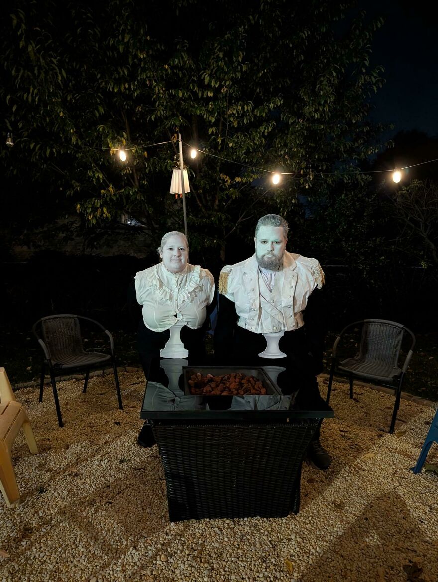 Couple dressed up as living white busts for a creative Halloween costume idea.