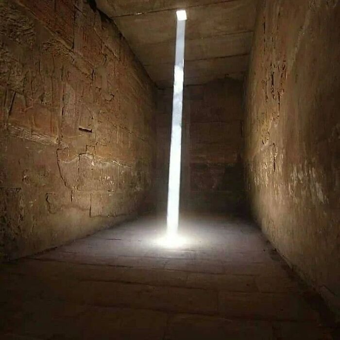 Single beam of sunlight shining into an ancient stone temple, showing facts about the past