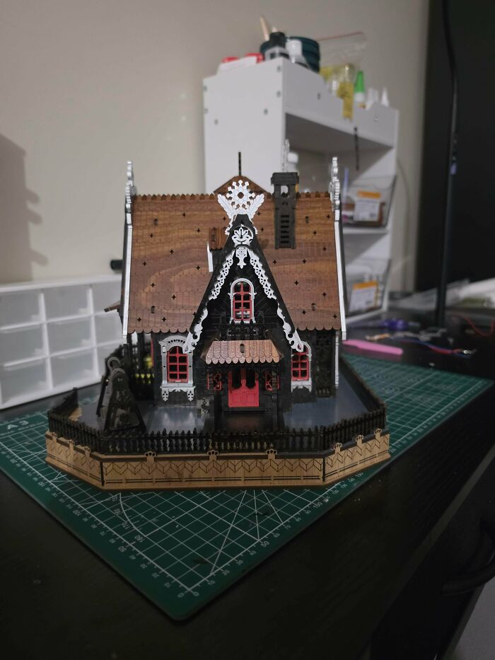 A charming gingerbread style miniature house book nook placed on a green cutting mat.