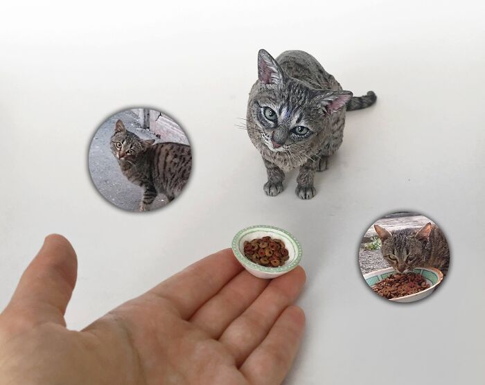 Handheld miniature display featuring a hyperrealistic sculpture of a tabby cat next to a food bowl