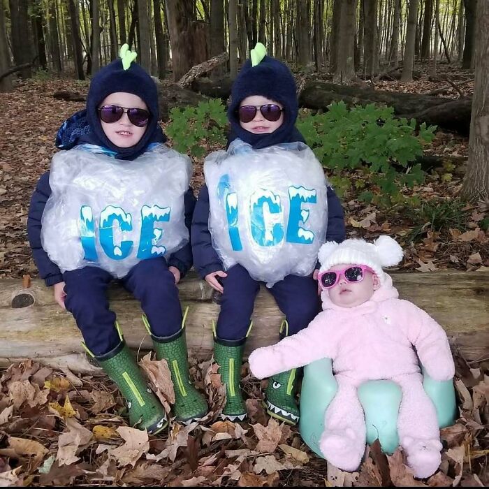Three siblings wearing funny Ice Ice Baby Halloween costumes while sitting outside in autumn leaves.