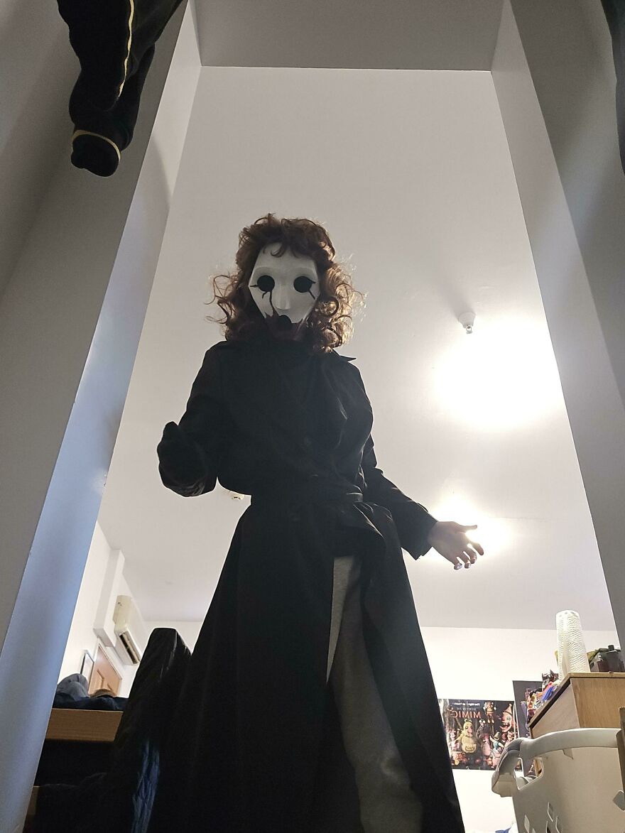 Scary masked figure wearing a long black coat for a creative Halloween costume