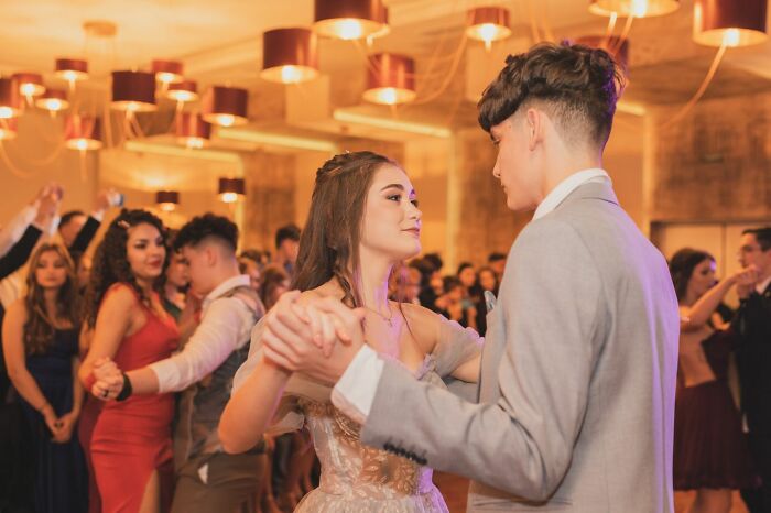 A teenage couple slow dancing at a prom, hinting at memorable relationship stories.