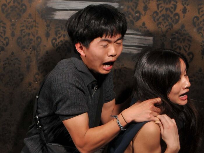 Terrified man clinging to a woman inside a haunted house photo