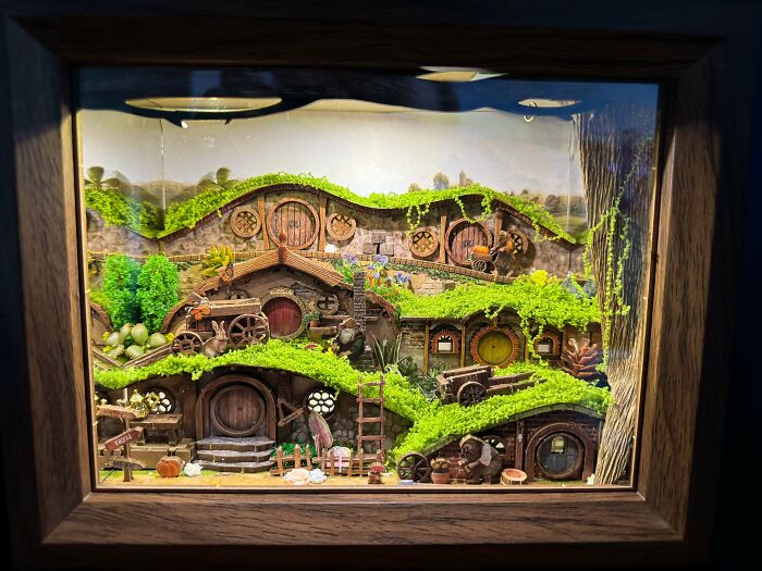 A charming Lord of the Rings-inspired book nook showcasing Shire-like hobbit holes with mossy green roofs.