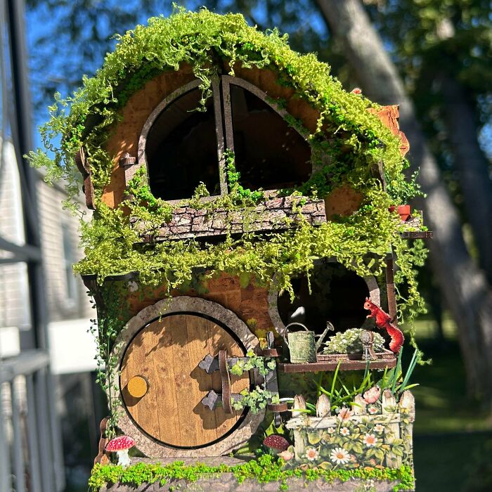 A whimsical mossy hobbit hole book nook with a round wooden door