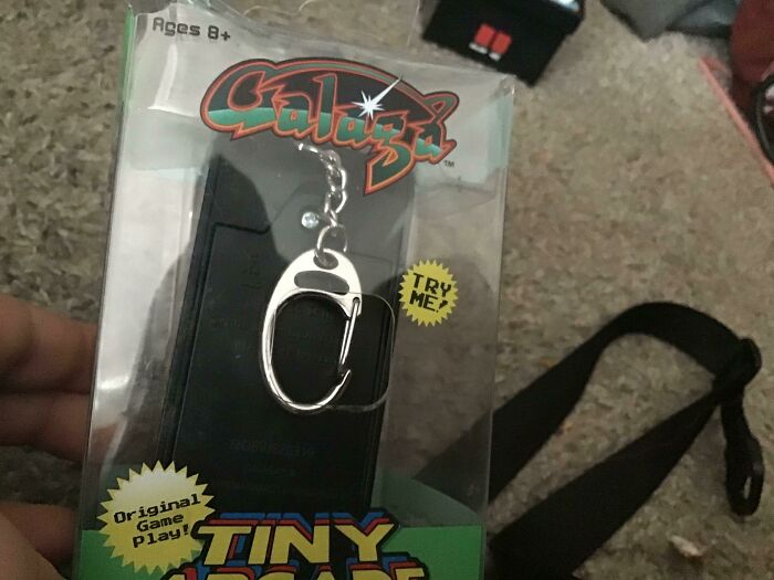 A Galaga tiny arcade keychain packaged upside down in a plastic box as a packaging fail