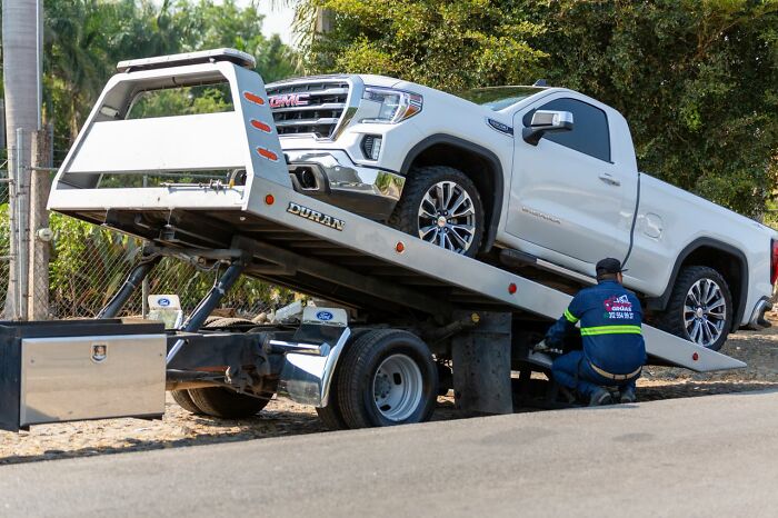 A white truck is loaded onto a flatbed tow truck, showing potential for relationship revenge.