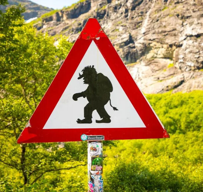 Red triangular road sign featuring a troll silhouette as a funny mistake from around the world.