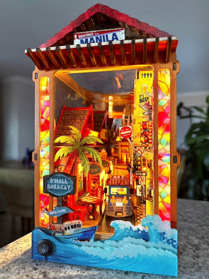 A colorful Manila and Boracay themed book nook with a tiny jeepney, palm tree, and bright lights.