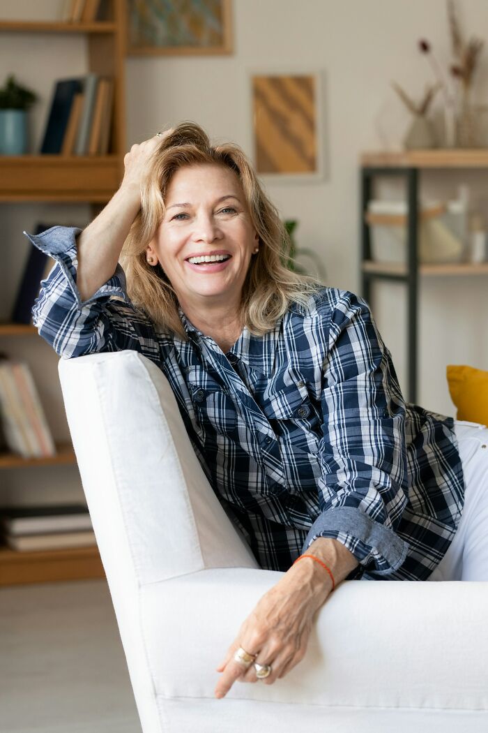 A smiling woman rests on a white armchair, reflecting on the reasons marriages collapsed and moving forward
