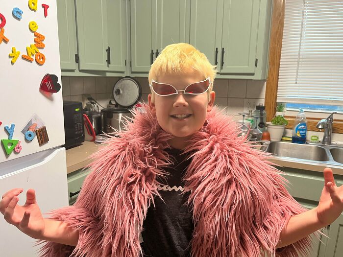 A boy dressed up in a pink fluffy coat and unique sunglasses for creative Halloween costumes.