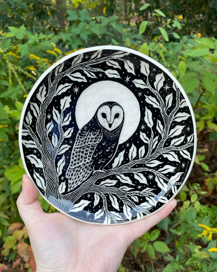 Hand-carved black and white ceramic plate featuring an owl under the moon, an artistic pottery creation.