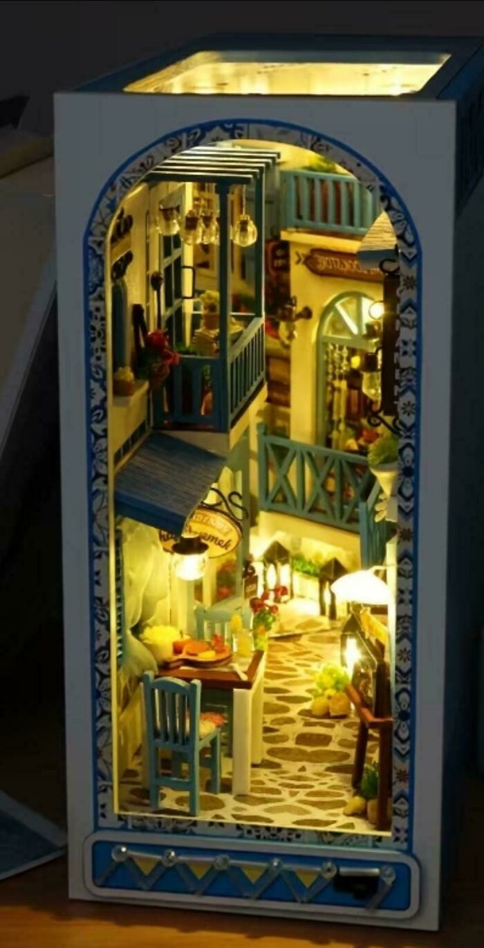 A glowing book nook miniature depicting a cozy Mediterranean street with balconies and dining tables