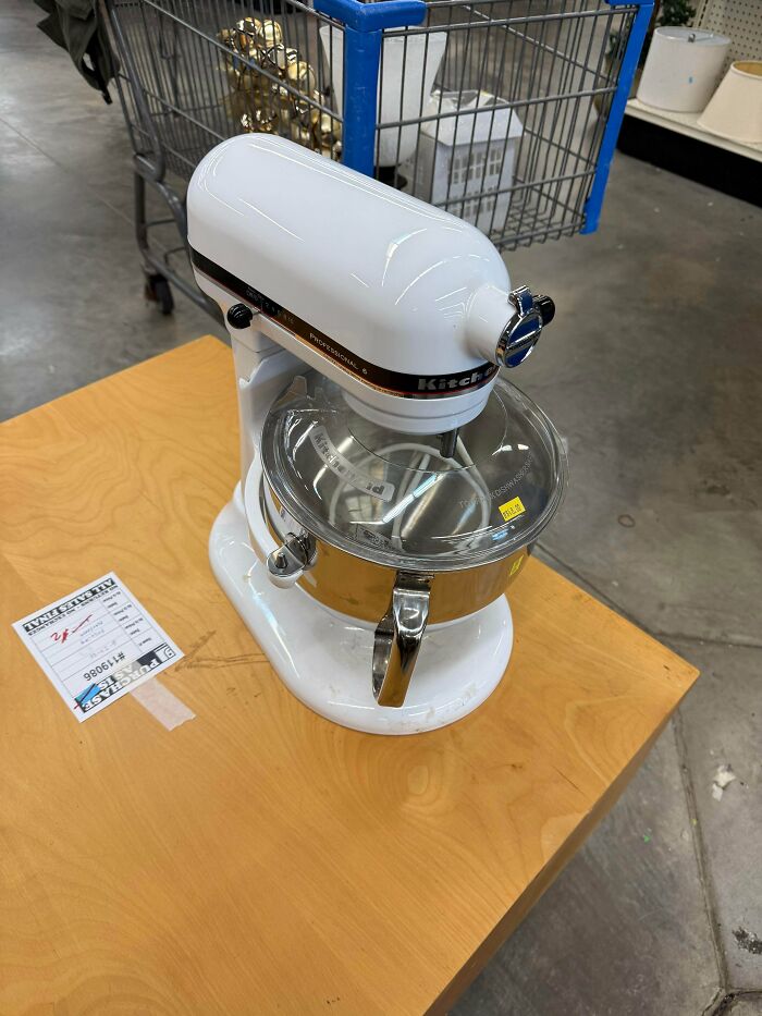 A white KitchenAid stand mixer sitting on a wooden table, one of the best thrift store finds.