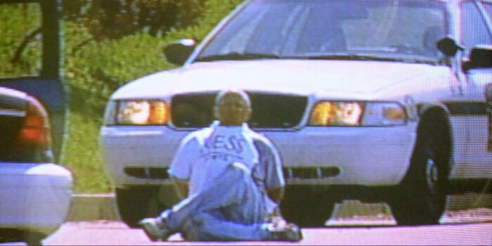 A man sitting on the ground in front of a car, captured in photos during a police encounter.