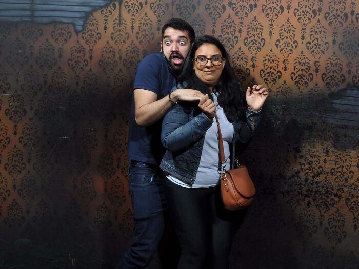 Terrified couple clinging together in fear for a funny haunted house photo inside Nightmares Fear Factory.