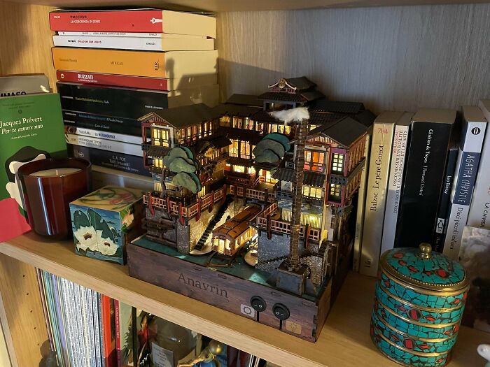 A detailed Japanese bathhouse book nook model glowing on a wooden shelf
