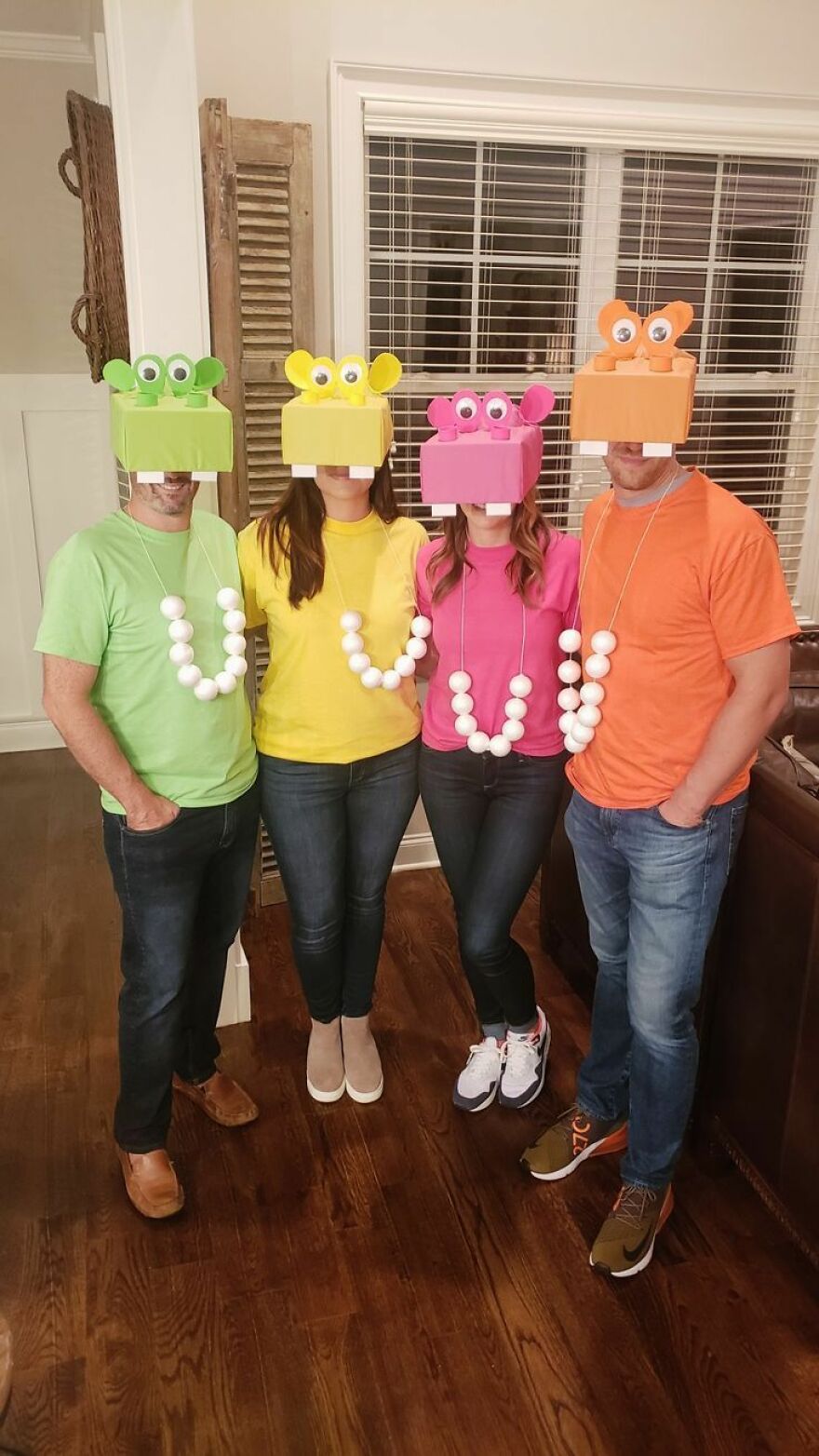 Four people wearing colorful Hungry Hungry Hippos boxes, showcasing group Halloween costume ideas.