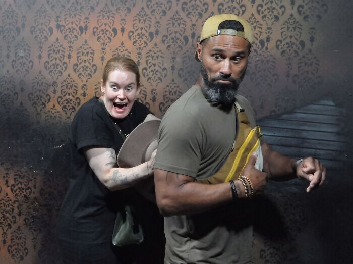 Funny haunted house photo of a woman screaming behind a surprised man with a hat