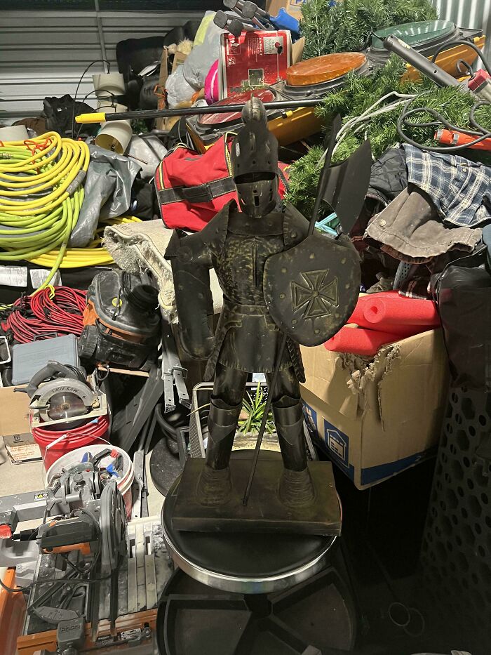 A miniature decorative metal knight statue holding a shield, among unique thrift store finds.