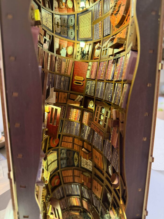A curved library miniature book nook showing rows of books and warm interior lighting
