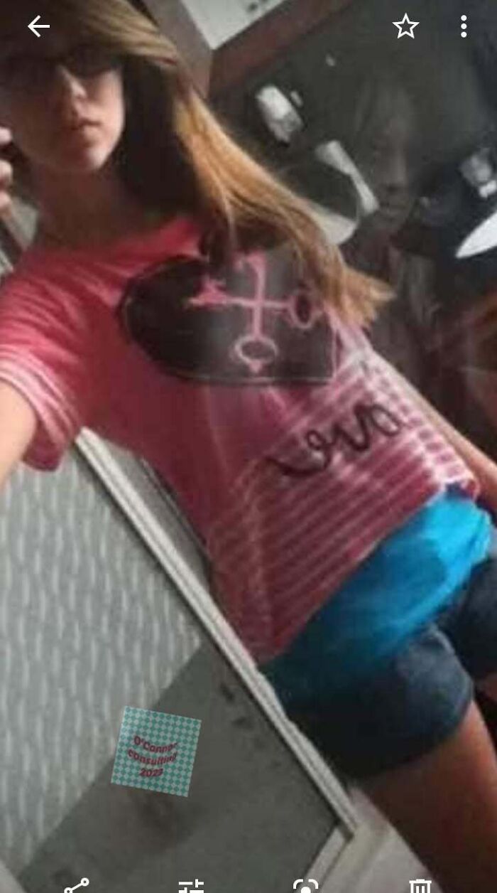 Girl taking a selfie with a creepy faint reflection behind her, giving horror movie vibes
