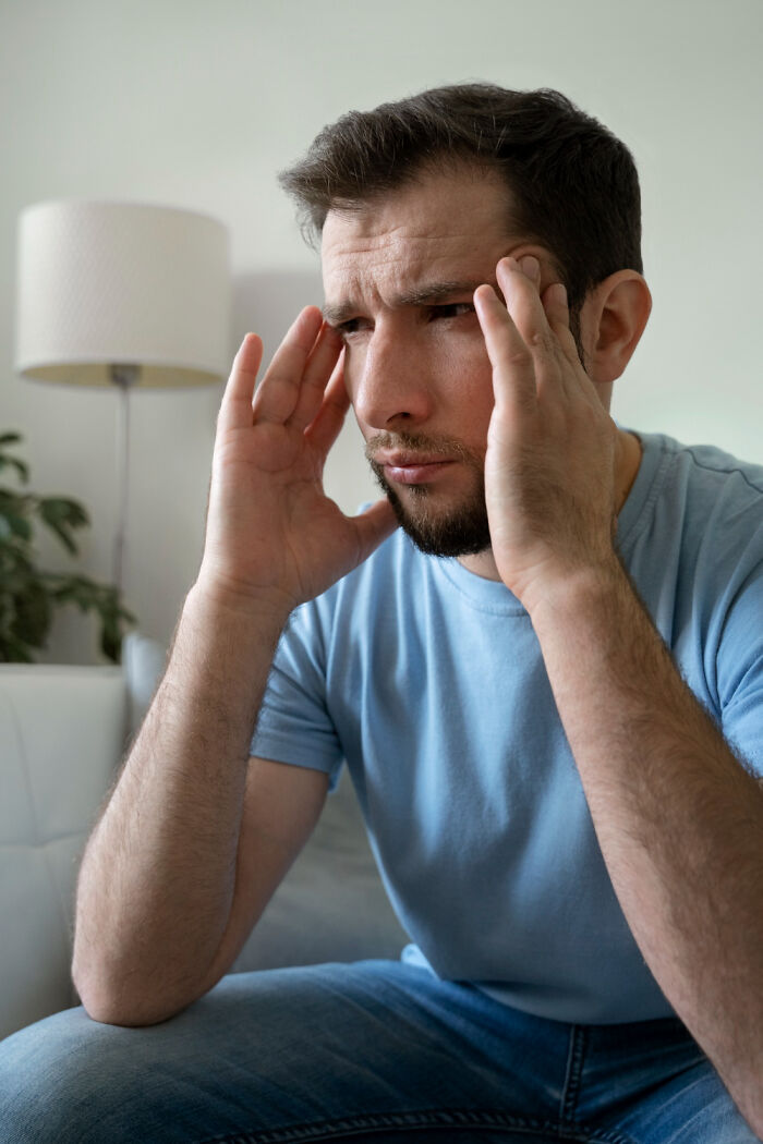 Stressed man holding his temples, reflecting tough relationship revenge stories