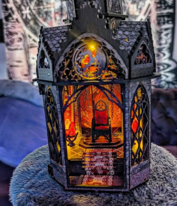 Intricate gothic throne room book nook with a miniature red seat illuminated by warm lights