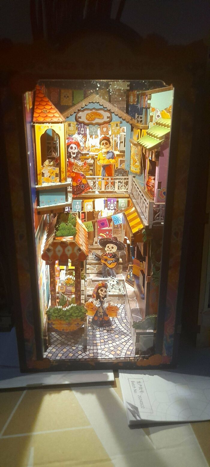 A vibrant Dia de los Muertos themed book nook with miniature skeleton figures and colorful decorations