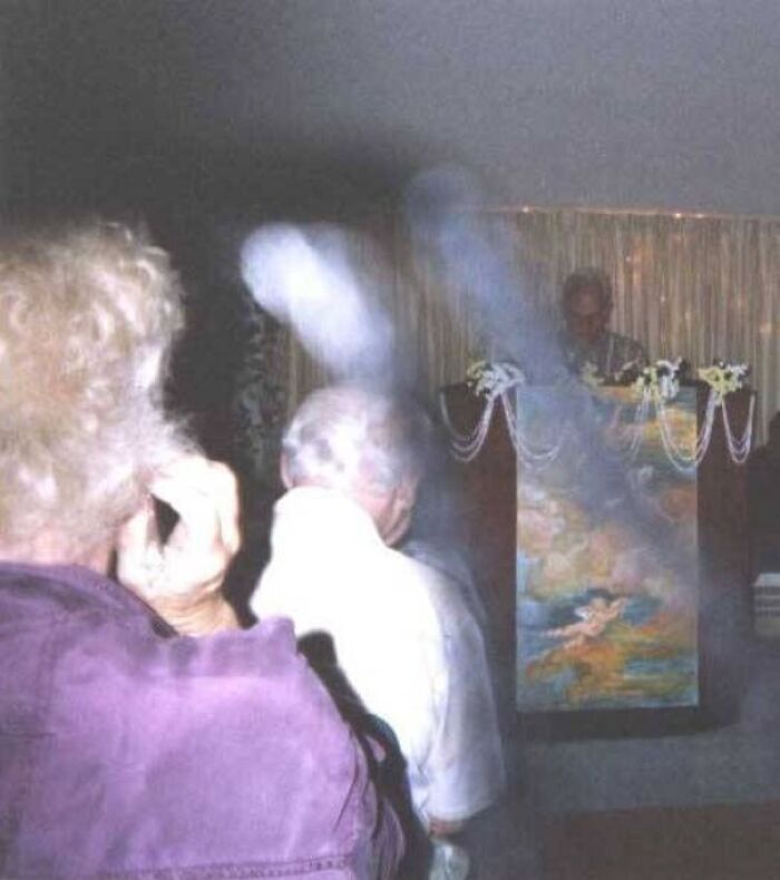 Glowing mysterious light wisps hovering over people in a room resembling a horror movie scene