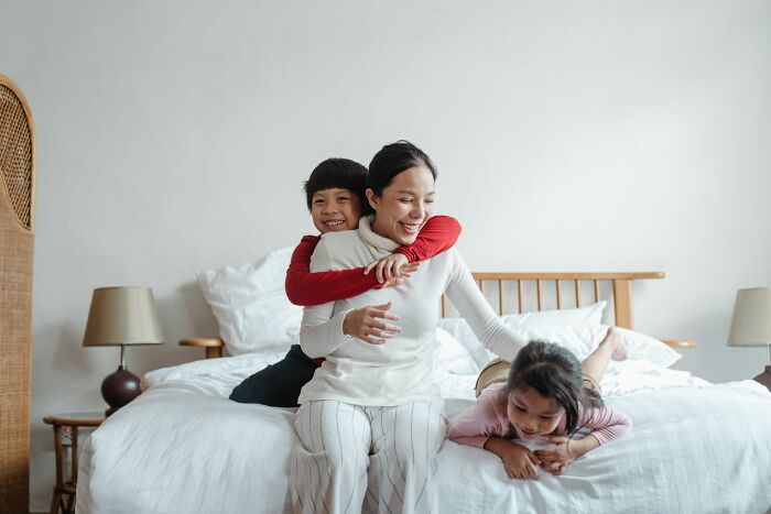 A happy mother with her children on a bed, finding peace after marriages collapsed
