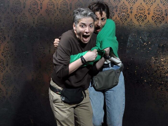 Two women terrified and clinging to each other in a haunted house photo.