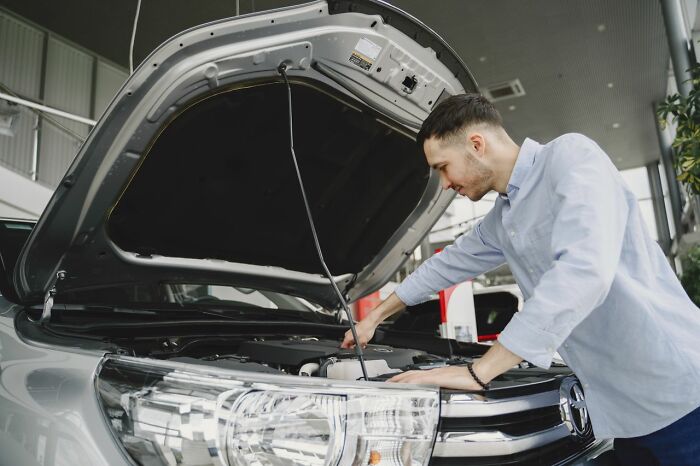 A man inspecting his car engine under the hood, reflecting on dramatic relationship revenge stories.