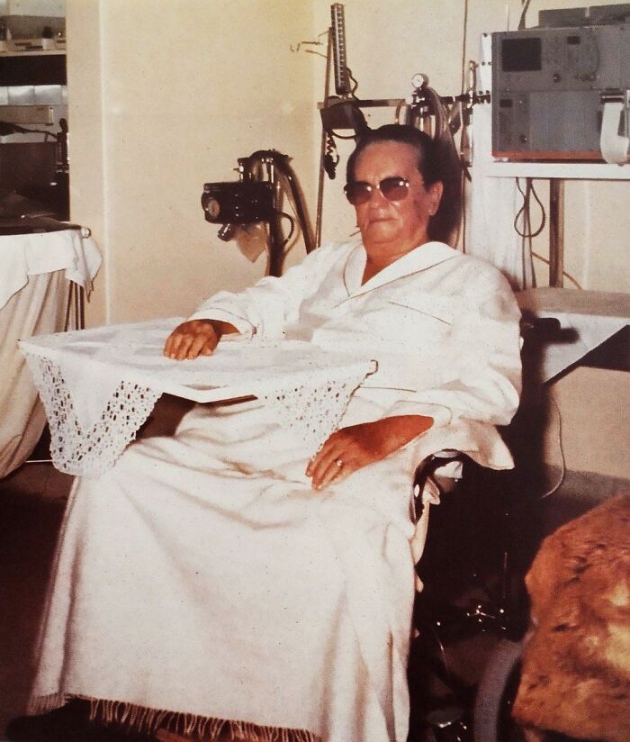 An elderly woman wearing sunglasses sitting in a wheelchair, one of the people captured in photos for the last time.