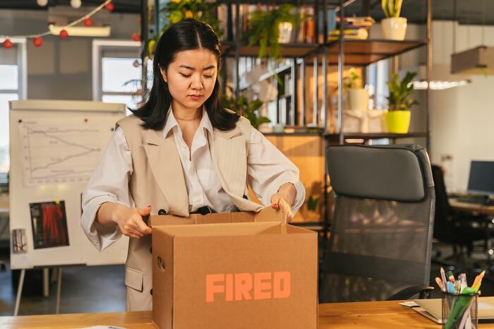 Sad woman packing her belongings after being fired, a reminder of relationship revenge stories.
