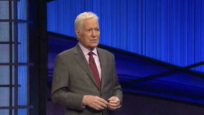 Alex Trebek standing on the Jeopardy game show set, captured in photos for the last time as a host