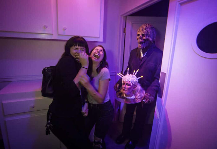 Two terrified women screaming near a monster in a haunted house photo.