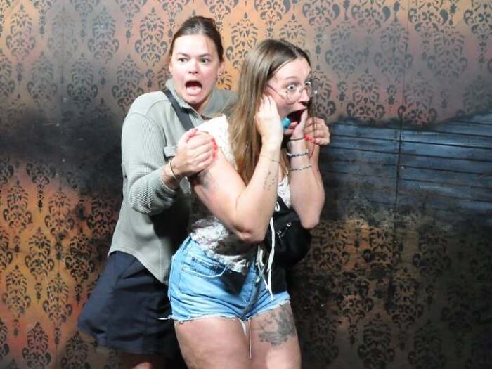Scared women in a haunted house photo clutching each other in fear.
