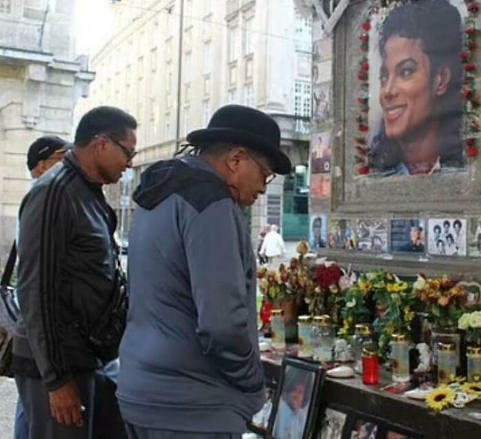 A man wearing a hat standing in front of a Michael Jackson memorial captured in photo for the last time