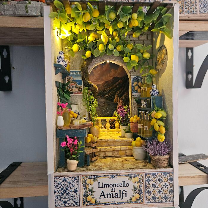 An Amalfi coast themed book nook featuring yellow lemons, shelves of bottles, and a stone archway.