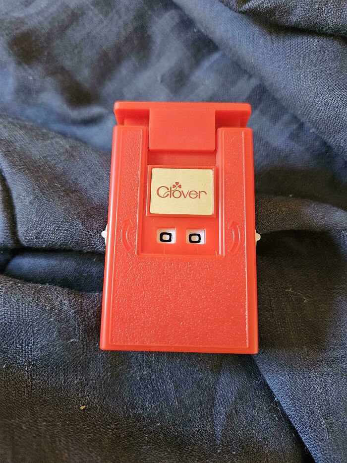 A small red Clover device sitting on a textured dark fabric.