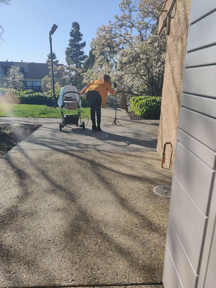 Influencer sets up camera tripod next to baby stroller in public spaces for photo shoot