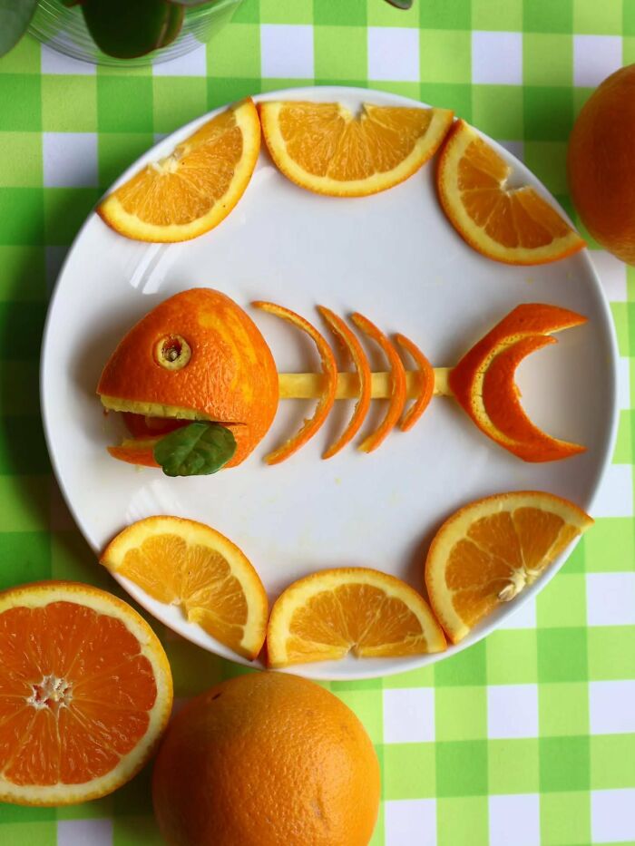 Orange peel fish skeleton food art by Sarah Rosado, surrounded by circular orange slices on a white plate.
