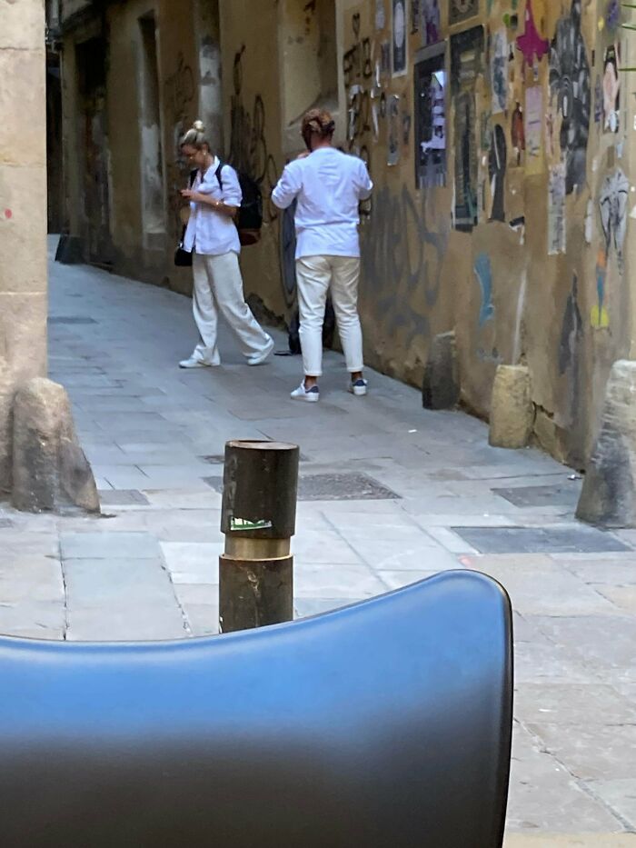 Influencers taking photos in narrow public alleyways lined with posters.