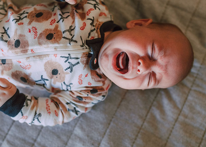 A newborn infant crying while lying down after giving birth