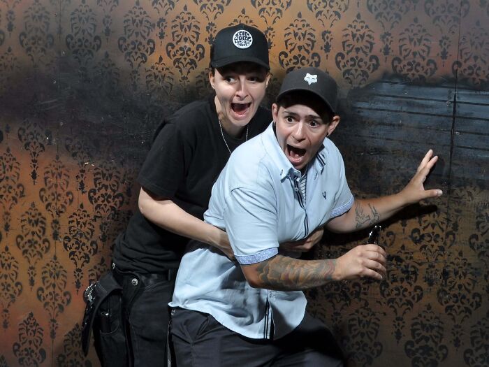 Two friends wearing caps looking terrified in a candid haunted house photo