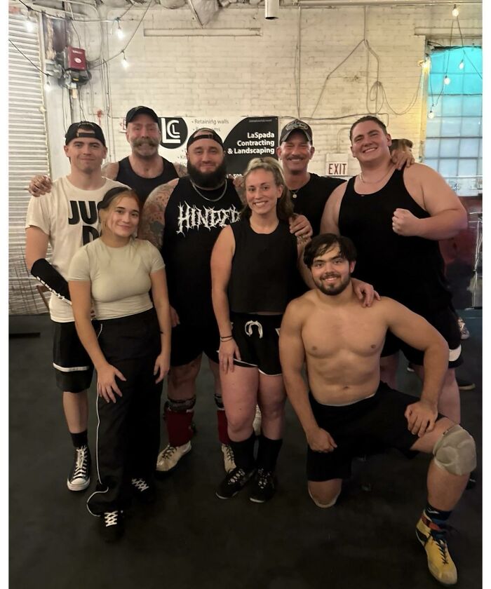 Group of friends and athletes posing together in a gym captured in photo for the last time