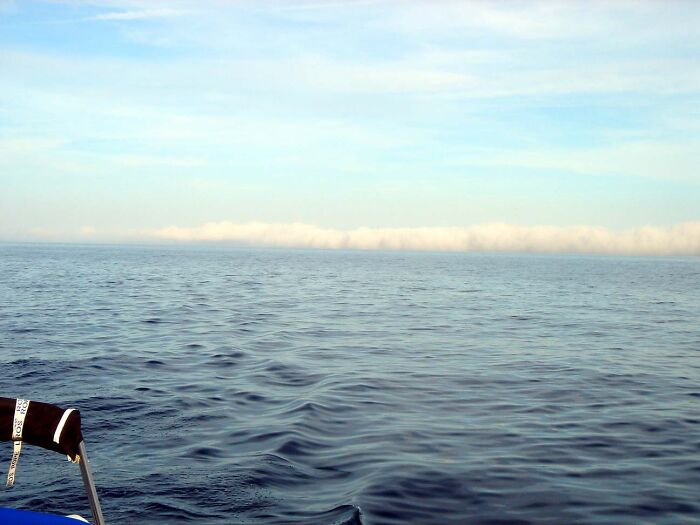 A wide ocean view showing a low horizontal band of clouds, typical of the bottom of the ocean