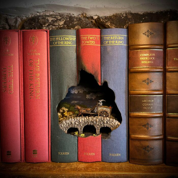 A Lord of the Rings book nook built into hollowed out fantasy books showing a carriage on a bridge